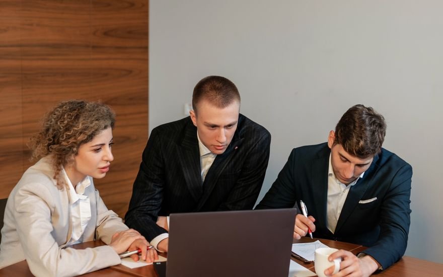 Tres compañeros de un equipo comercial repasando datos en un portátil